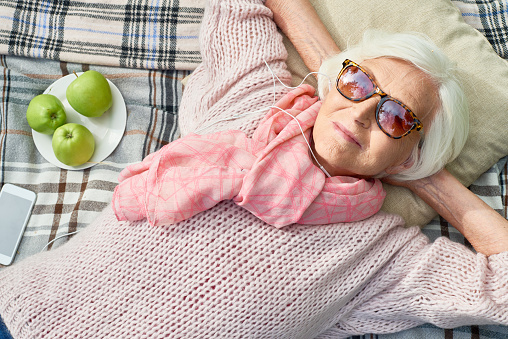 Mujer Senior feliz escuchando música en Picnic photo