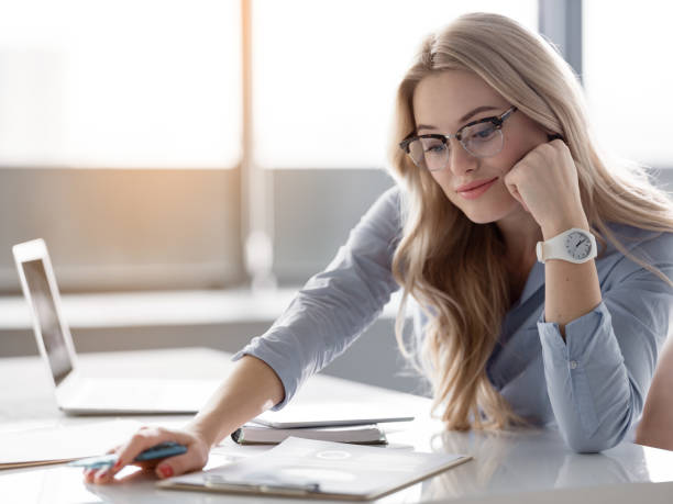 istock Cheerful blond woman analyzing papers at workplace 948285634