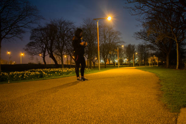 istock Woman standing on path in park at night preparing for jogging or running 948286724