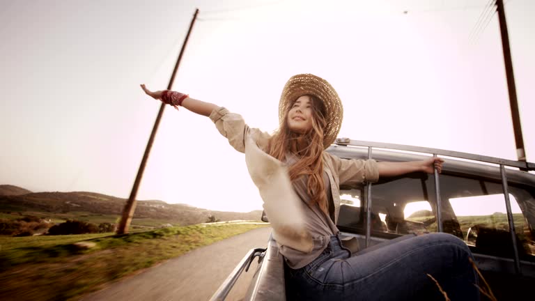 Beautiful woman sitting with outstretched arms in a pick-up truck