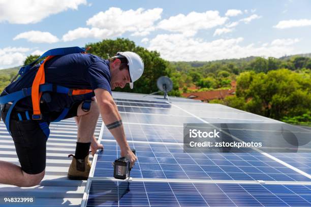Solar Panel Technician With Drill Installing Solar Panels Stock Photo - Download Image Now