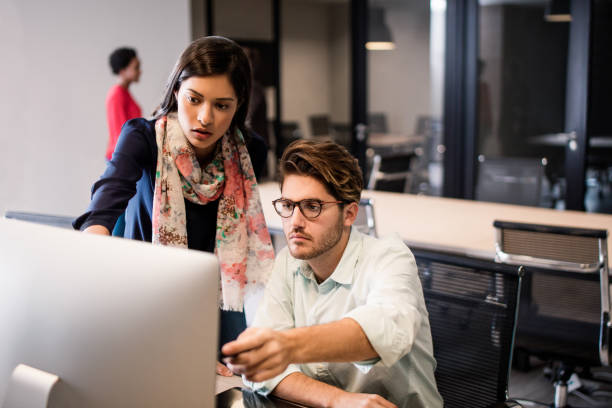 istock Serious latin young man and woman looking at computer 948324388