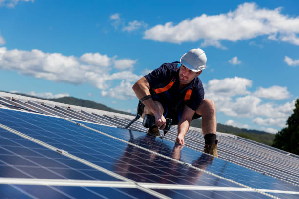 Solar panel installer with drill installing solar panels Solar panel installer with drill installing solar panels on roof on a sunny day rooftop solar stock pictures, royalty-free photos & images