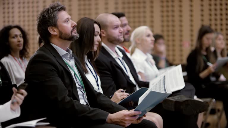 People at a seminar listening to the speakers and making notes