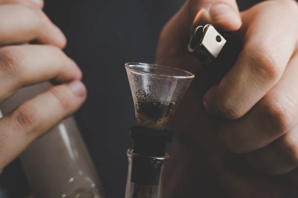 istock A man smokes cannabis weed, a joint and a lighter in his hands. Smoke on a black background. Concepts of medical marijuana use and legalization of the cannabis. 948351752