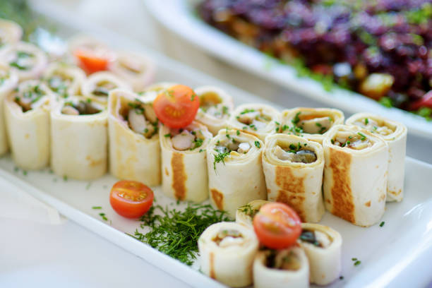 Delicious pork rolls with vegetables served on a party or wedding reception. Plates with assorted fancy finger food snacks on an event party or dinner.
