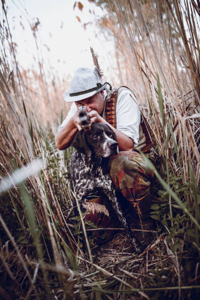 istock Hunter with his Dog Hiding in the Reed Waiting for Action 948355194