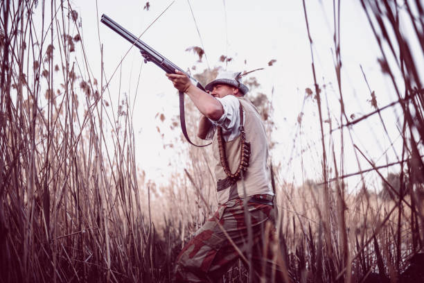 istock Male Hunter Hidden in the Swamp and Preparing for Shooting 948355596