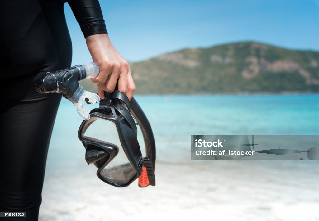 Diving goggles and snorkel gear in hand near beach Snorkeling Stock Photo