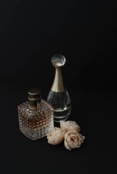 istock Bottle Perfume and Fake White Roses on dark Black Background with copy Space Text Vertical Image 948386962
