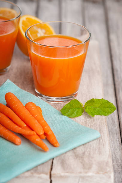 istock Glasses with carrot juice, sliced orange and mint leaf 948388138
