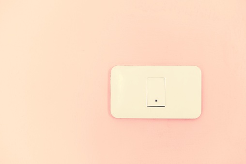 White light switch electric power supply on pink wall