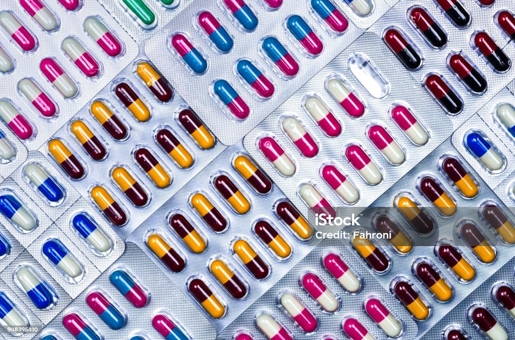 Full frame of colorful antimicrobial capsule pills. Quality control error in pharmaceutical manufacturing. Blister pack missing one capsule of antibiotic pill. Drug resistance. Defective concept. Medicine Stock Photo