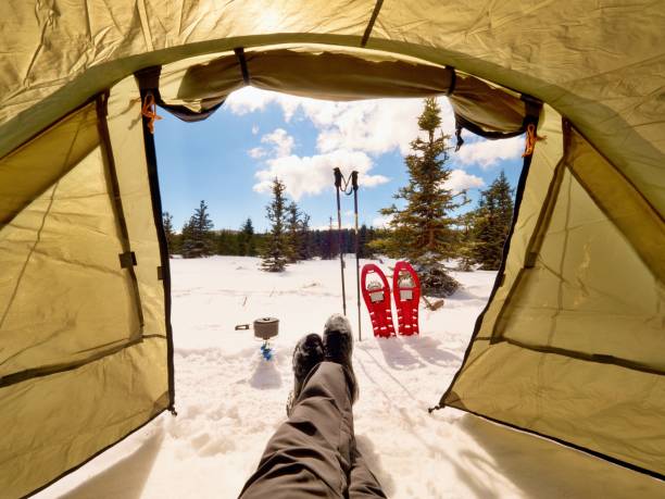 istock Man relaxing. Winter view from camping  tent entrance out 948404378