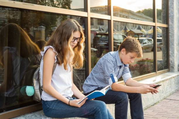istock Children teenagers, break reading book and using smartphone. 948404602