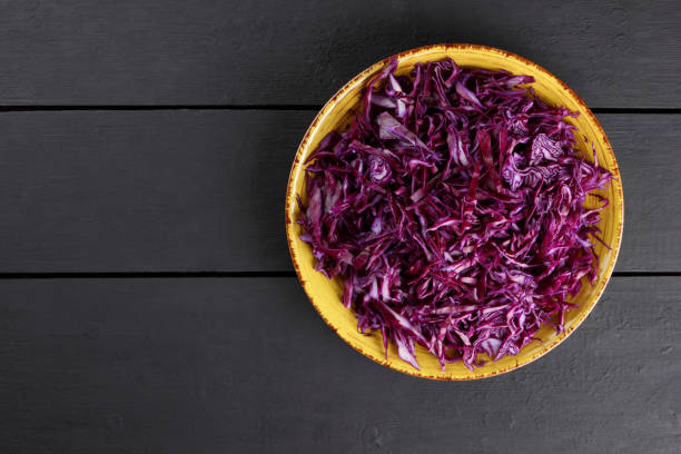 istock Chopped purple cabbage on a black background, red cabbage on a yellow plate, copy space, top view, vegetarian food, fresh vegetables on dark boards, minimalism 948404678