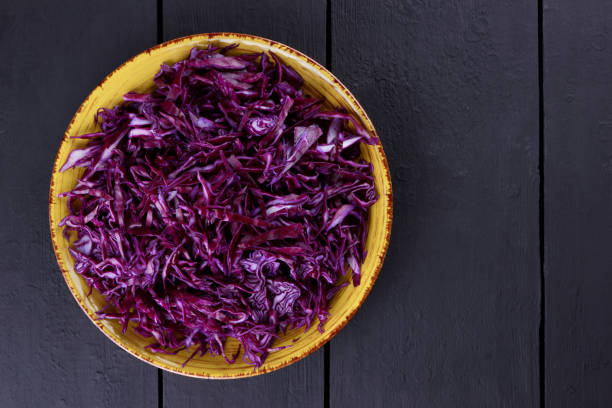 istock Chopped purple cabbage on a black background, red cabbage on a yellow plate, copy space, top view, vegetarian food, fresh vegetables on dark boards, minimalism 948404700