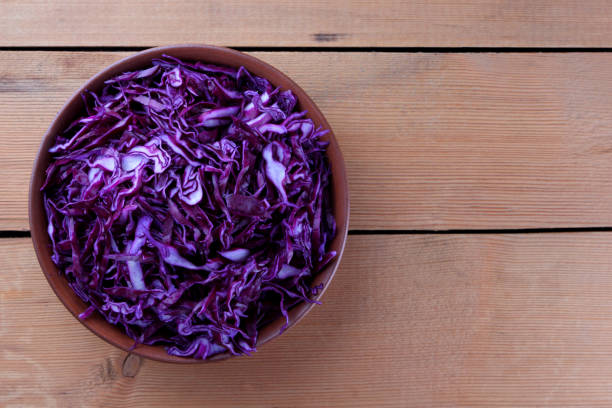 istock Chopped purple cabbage on a wooden background, red cabbage in a clay bowl, copy space, rustic style, vegetarian food, half fresh cabbage, minimalism 948408456