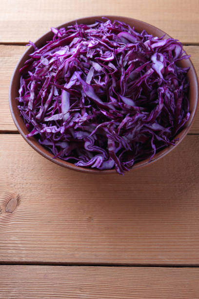 istock Chopped purple cabbage on a wooden background, red cabbage in a clay bowl, copy space, rustic style, vegetarian food, half fresh cabbage, minimalism 948408496