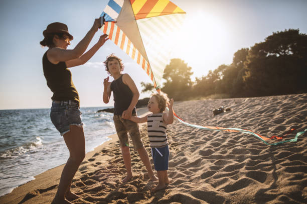 istock Mother and her sons flying a kite at the beach 948411264