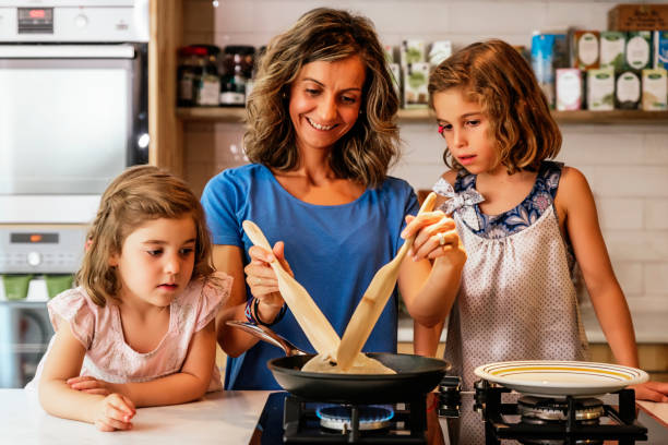 istock Little sisters cooking with her mother in the kitchen. 948417112