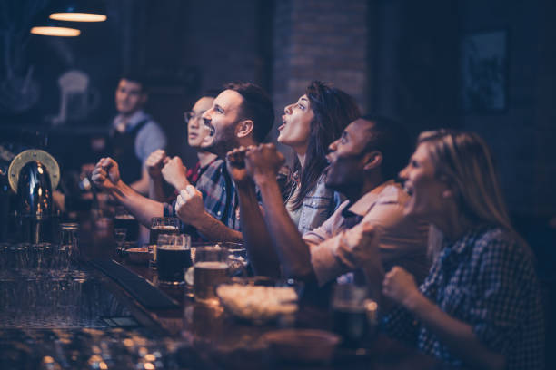 istock Young excited fans having fun in a bar while cheering for their favorite team. 948418046