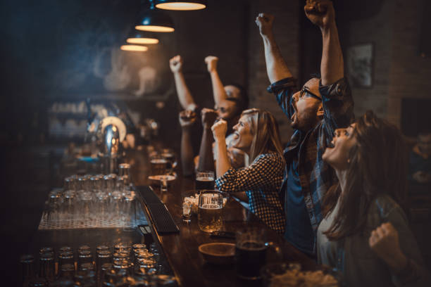 Goaaaaaaal! Large group of excited fans celebrating success of their sports team while watching a game in a bar. pub stock pictures, royalty-free photos & images
