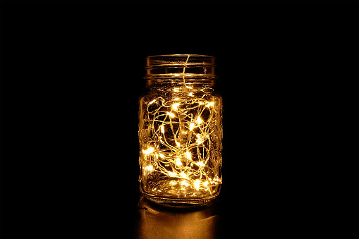 Yellow Fairy Light in Glass Mason Jar on Dark Background