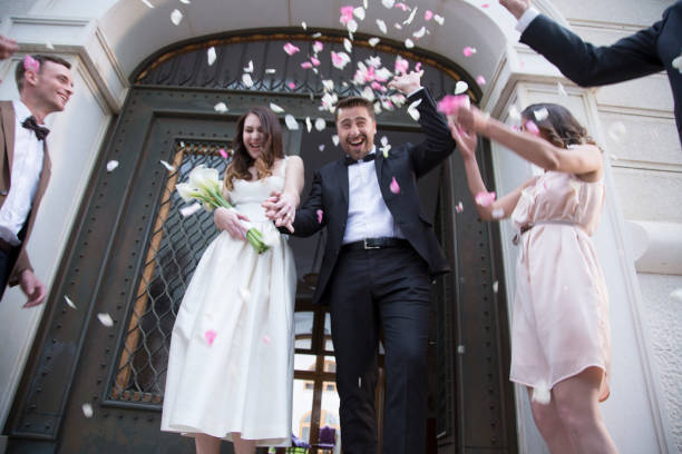 istock Guests throwing rose petals on bride and groom 948424208