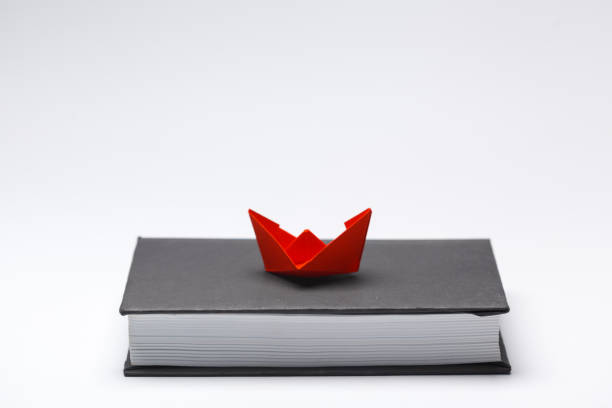 istock Origami paper boat on a book 948430290