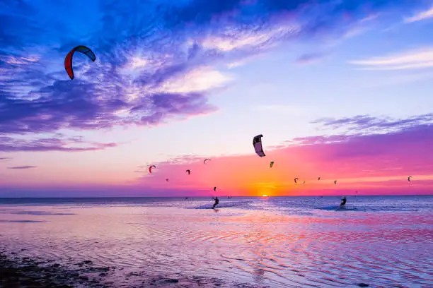 Photo of Kite-surfing against a beautiful sunset. Many silhouettes of kites in the sky. Holidays on nature. Artistic picture. Beauty world.