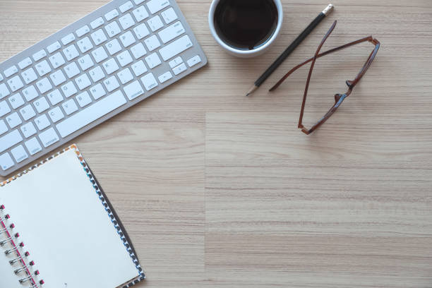istock Graphic design office desk workplace with coffee cup, notepad and glasses on wooden background. Top view with copy space 948430888