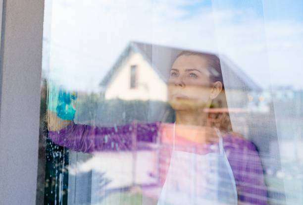 istock Young beautiful woman in white apron cleaning windows. 948444018