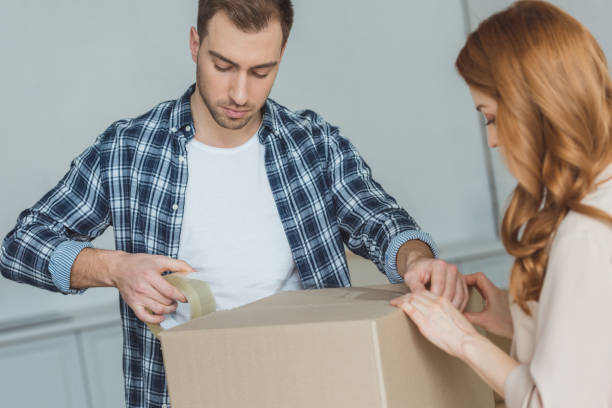 istock couple packing cardboard box with sticky tape together, relocation concept 948444066