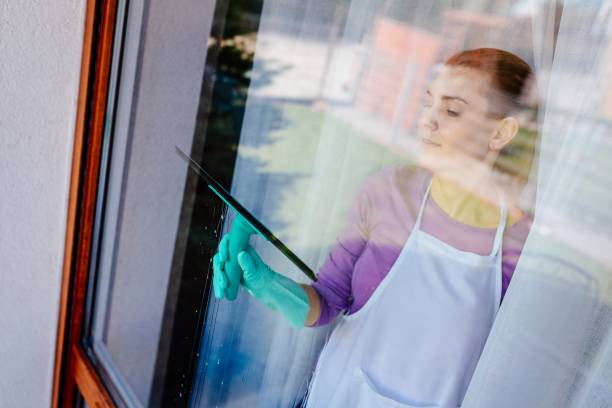 istock Young beautiful woman in white apron cleaning windows. 948444094
