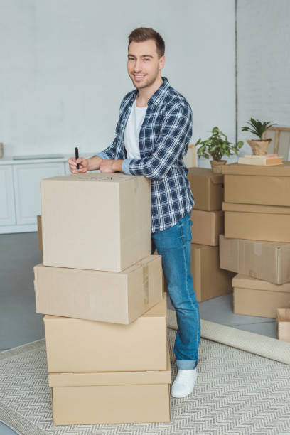 istock smiling man signing cardboard box for moving home, relocation concept 948444098