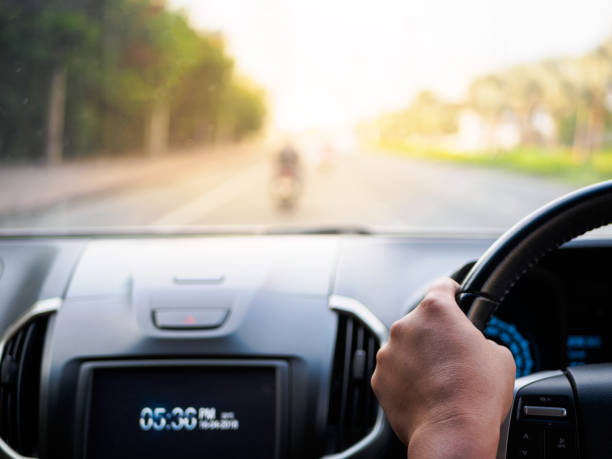 istock Man's hands holding steering wheel and blur road background. Driving concept 948445282