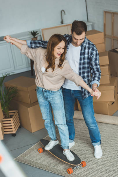 istock young couple having fun with skateboard at new apartment with cardboard boxes, relocation concept 948447486