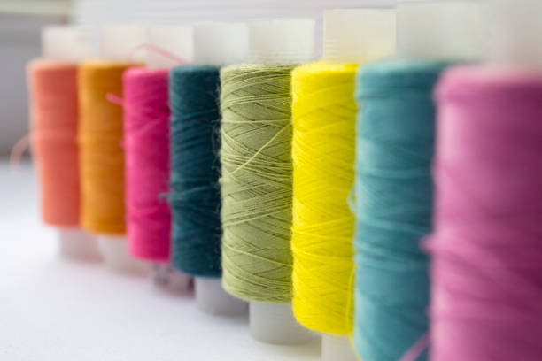 istock Various colored threads with clothes buttons on white cardboard background. Macro photo 948456266