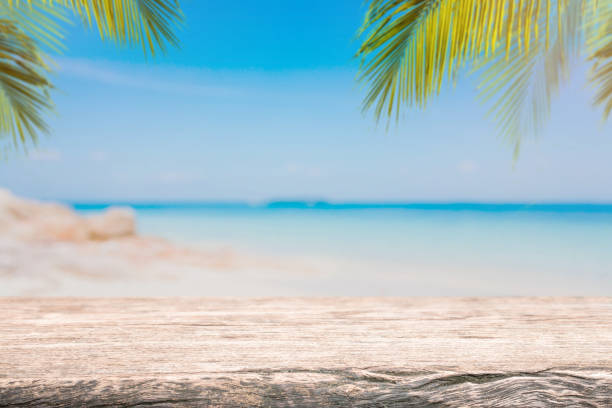 istock Empty wood table top and blurred Palm tree summer beach with blue sea and sky background. - can used for display or montage your products. 948456326