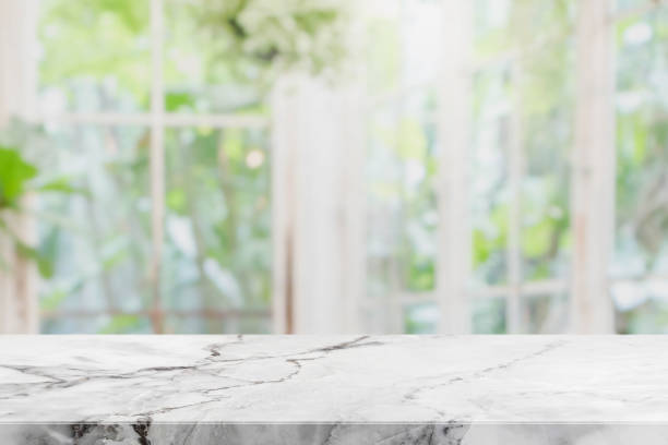 istock Empty white stone marble table top and blurred of interior room with window view green from tree garden background background - can used for display or montage your products. 948456352