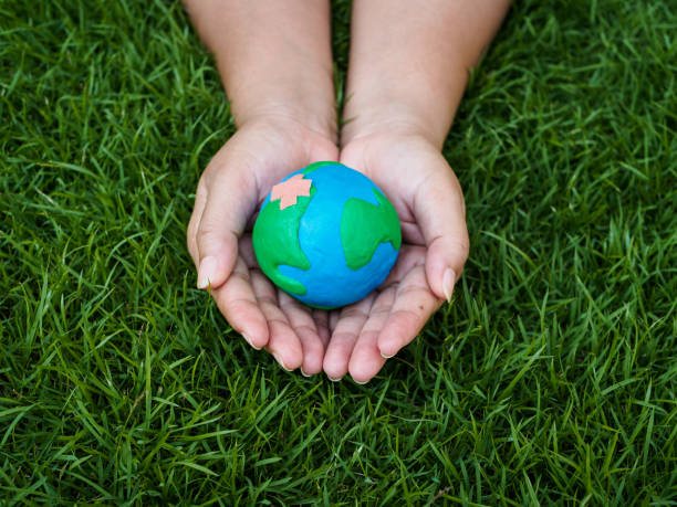 istock earth day. earth in hands and green grass field background. environment save earth concept. 948459356