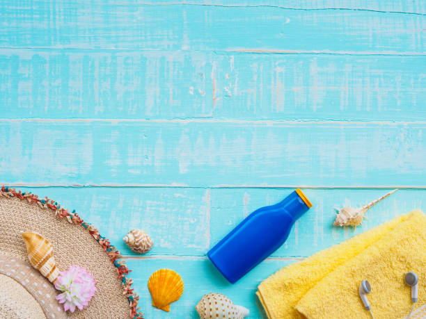 istock Beach accessories including sunscreen, hat beach, shell, yellow towel and earphones on bright blue pastel wooden background for summer holiday and vacation concept. 948459544