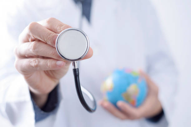 doctor man with a stethoscope and a world globe closeup of a young caucasian doctor man with a world globe in one hand and a stethoscope in the other hand Travel Health Insurance stock pictures, royalty-free photos & images