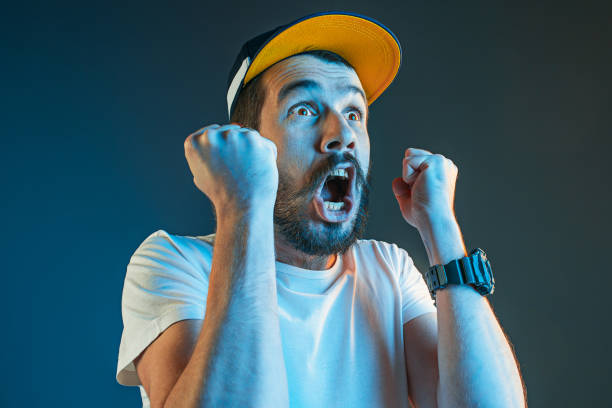 The anger and screaming man The anger and screaming man. Hate, rage. Crying emotional angry man in colorful bright lights at studio background. Emotional face. Fan human emotions, facial expression concept. football fans stock pictures, royalty-free photos & images