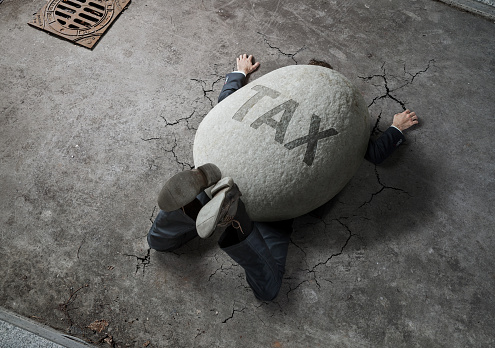Tax concept, high angle view of businessman crushed by the huge stone on the street
