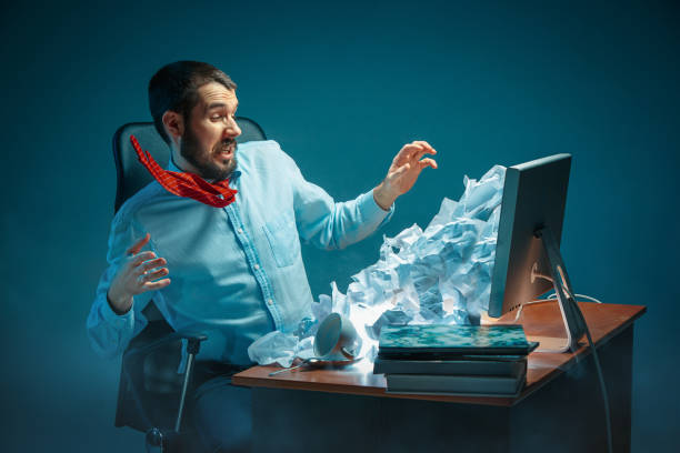 istock Young stressed handsome businessman working at desk in modern office shouting at laptop screen and being angry about spam 948476032