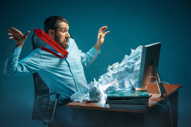 Young stressed handsome businessman working at desk in modern office shouting at laptop screen and being angry about spam Young stressed handsome businessman working at desk in modern office shouting at laptop screen and being angry about e-mail spam. Collage with a mountain of crumpled paper. Business, internet concept overflow stock pictures, royalty-free photos & images