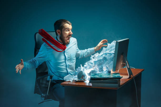 istock Young stressed handsome businessman working at desk in modern office shouting at laptop screen and being angry about spam 948480720