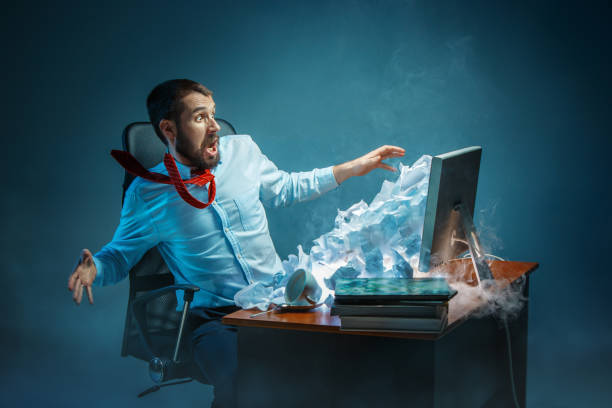 istock Young stressed handsome businessman working at desk in modern office shouting at laptop screen and being angry about spam 948480934